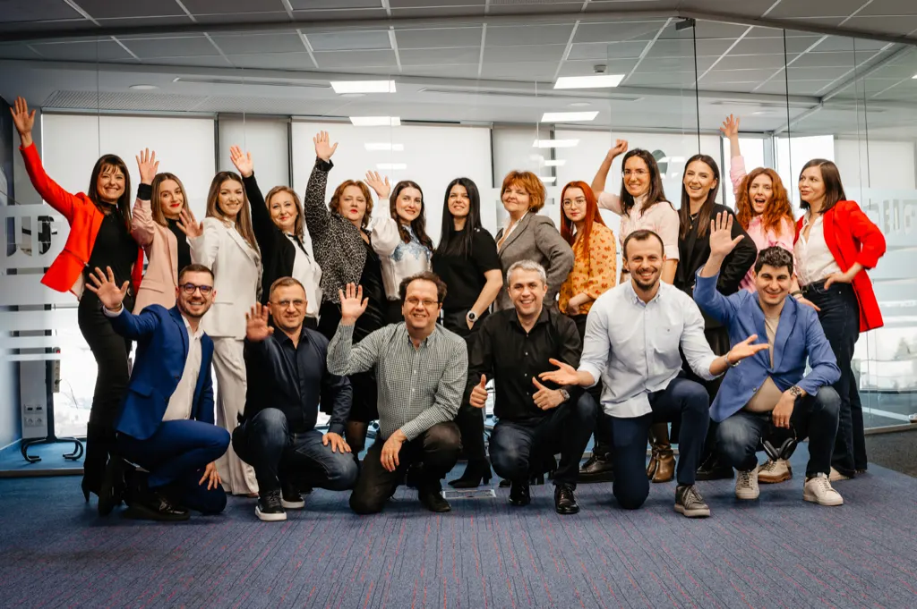 Echipa DWF, zâmbind și salutând, în biroul agenției din București