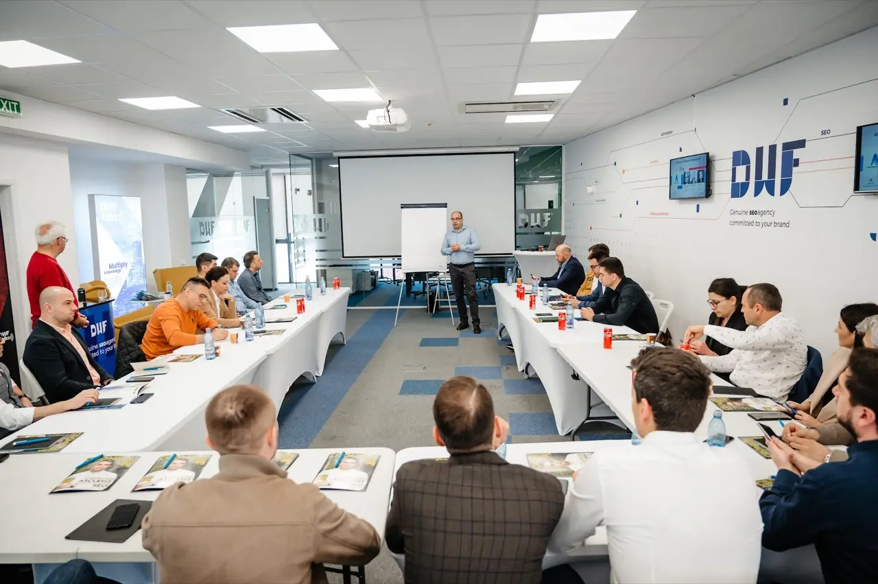 Sala plină în timpul atelierului, cu logo-ul DWF pe perete