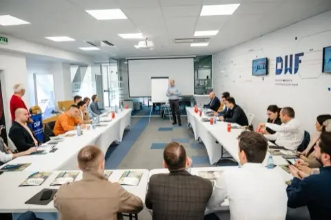 Sala plină în timpul atelierului, cu logo-ul DWF pe perete