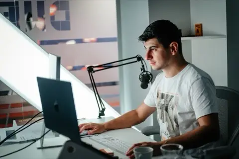 Participant lucrând la laptop lângă un microfon