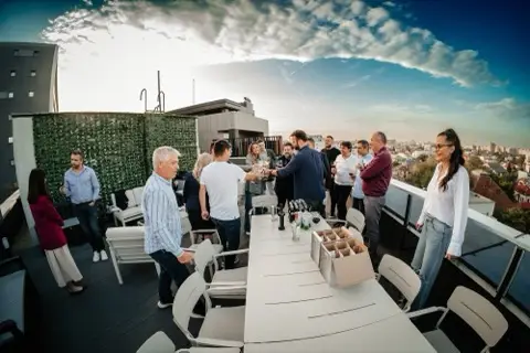 Participanți la networking pe terasă, la apus