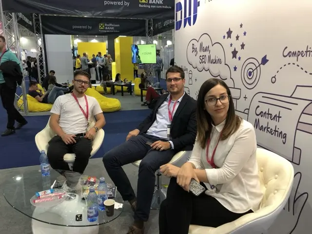Discuție pe fotoliile standului DWF, lângă ilustrația „Big, Mean, SEO Machine”